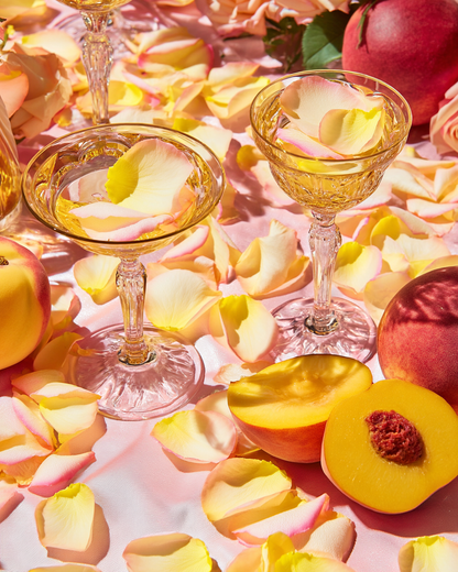 Coupes de champagne et pétales de rose jaune-rose avec pêches — ambiance estivale romantique | The Originea