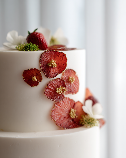 Bulk fraises séchées en pétales rouge profond sur gâteau de mariage à étages blanc épuré — décoration pâtisserie premium | The Originea