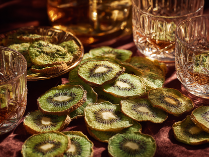 Bulk kiwi séché en tranches au cœur graphique vert près de verres cristal pour cocktail signature et mixologie | The Originea