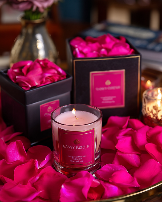Coffret et bougie The Originea sur lit de pétales de rose cerise foncé — confettis mariage de luxe