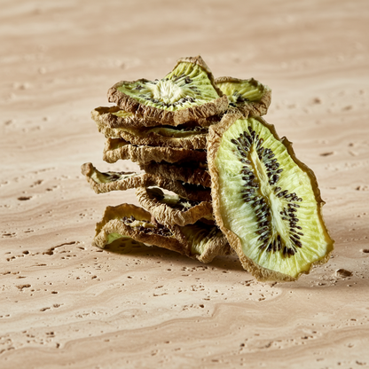 Tranches de kiwi séché disposées en décoration naturelle sur fond pierre avec branches d’olivier | The Originea