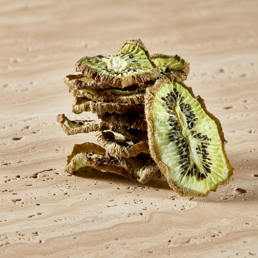 Tranches de kiwi séché disposées en décoration naturelle sur fond pierre avec branches d’olivier | The Originea