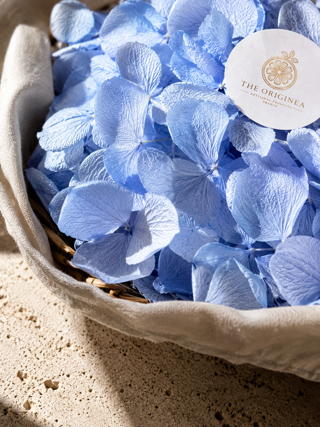 Pétales d'hortensias bleu clair séchés dans un panier en osier avec linge naturel — confettis mariage biodégradables The Originea