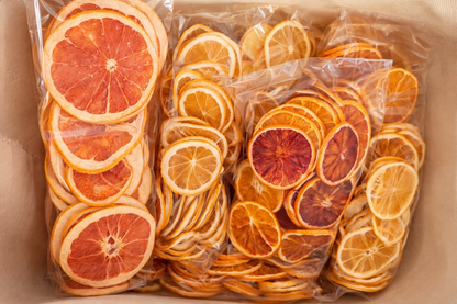 Vue du dessus de trois sachets transparents de tranches d'agrumes deshydratees : orange sanguine, citron et melange d'oranges dans une boite kraft