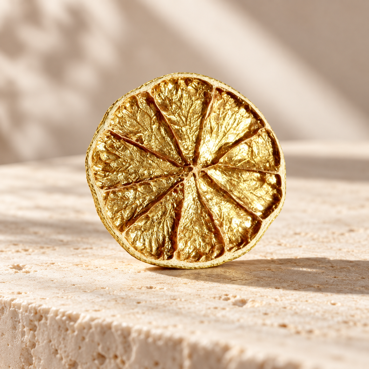 Gros plan tranche de citron vert dorée gold posée sur travertin | The Originea