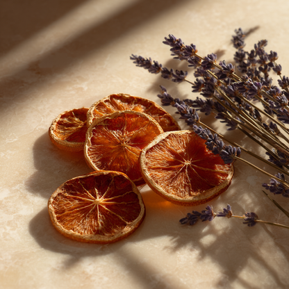 Quatre tranches de clementines corses deshydratees avec bouquet de lavande sechee sur marbre beige en lumiere naturelle doree